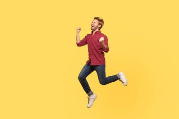 Enthusiastic overjoyed victorious guy in casual outfit jumping high trampoline, flying in air shouting for joy, celebrating victory. Life people energy concept. full length studio shot isolated