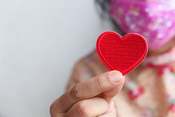 Women in protective face mask holding red heart with copy space 