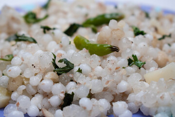 close up shot of traditional maharashtrian dish of sabudana khichdi with green chilly and vegetables on top