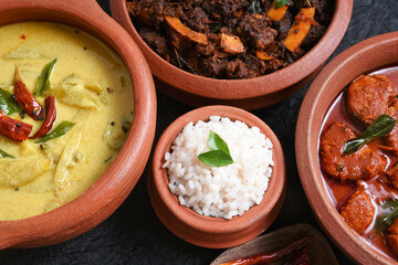 Traditional Kerala rice with side dish yellow mango curry, fish curry, beef roast Kerala India. Made from organic raw ripe mango, coconut milk, seasoned with curry leaves, Indian red Kashmir chilli.