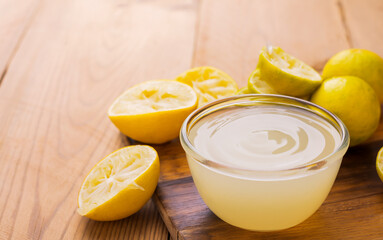 Freshly squeezed lemon juice in a small glass bowl Place on a wooden table that has a light sunlight shining on the back.