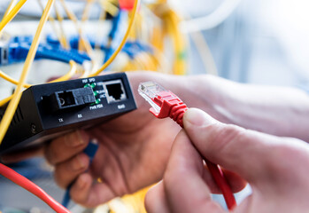 Network engineer working in server room. Connecting network cables to switches
