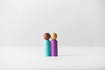 Wooden toy figurines concept. Mixed colour skin couple standing in the middle.   White caucasian person with black African American person. Different race couple, genders or age unknown.