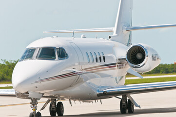 Front view far distance, of an executive, private jet, aircraft, with engine warming up before taking off, on tropical, island, airstrip, on the gulf of Mexico, on a sunny afternoon