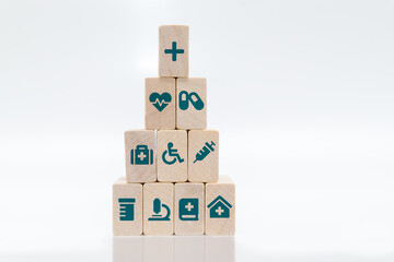 Health insurance concept. Medical symbols on wooden blocks stacked in a pyramid on white background.