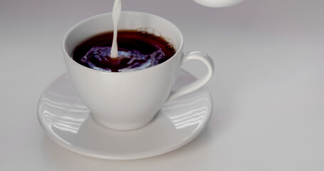 Pouring cream on an cup of coffee on a white background