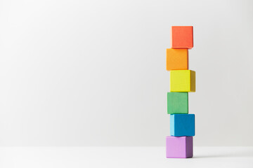 Wooden toys concept. Tower of wooden blocks in colours of the gay pride rainbow flag. Tower unevenly built.