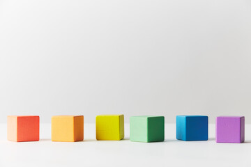 Wooden toys concept. Line of wooden blocks in colours of the gay pride rainbow flag. Blocks are scattered in one imperfect line