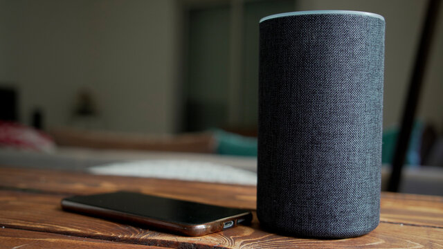 Dark grey Black Amazon Alexa Echo and smart phone on the wooden table in a living room,