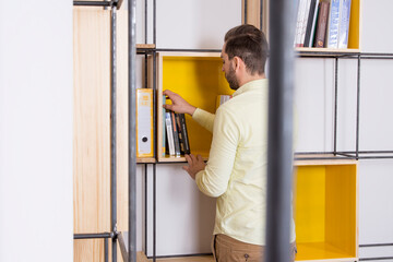 Fototapeta na wymiar Persona cogiendo libros en estantería moderna 