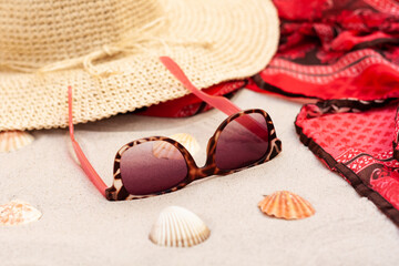 Vintage summer wicker straw beach hat, pareo and sunglasses on the seashore of Catania, Sicily, Italy.