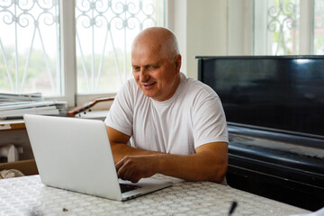 Elderly man with headphones and computer laughing happily, telework, e-business or commerce,...