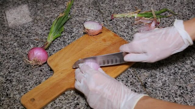 Chef's hands chopping onion and garlic seen from above