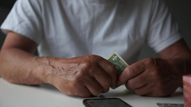 Man counting money savings due to economic financial crisis and unemployment looking at phone with currency rates and a calculator, income decrease