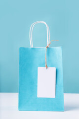 blue shopping bag with a blank white tag on white table