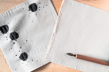 Tissue paper with black ink splash and dip pen on wooden table. tissue paper or note paper and space for text, list do it ,Suitable day or special occasion.Flat lay, Top view