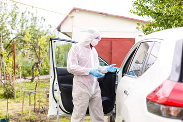 Man wearing a personal protective equipment suit, gloves, surgical mask and face shield, testing covid-19 coronavirus on another man sitting in a car.