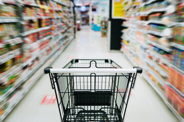 A close up of empty black shopping cart aisle are moving in supermarket aisle with motion blurred background, Business consumer lifestyle concept with copy space