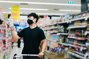 Young Asian man wear a black face mask are shopping in supermarket