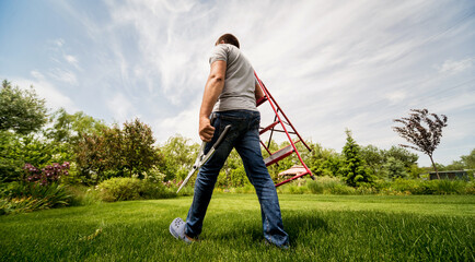 Professional gardener goes to cut trees with garden scissors and ladder