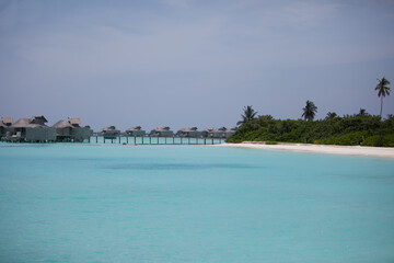 Maldivian water villas and island seen from turquoise ocean 