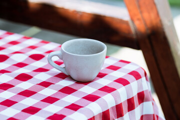cup on the background of a checkered tablecloth on the street, coffee on a picnic