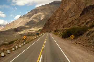 Travel. Asphalt highway in the mountains and valley on the road to mountain Aconcagua in Mendoza, Patagonia Argentina. The road crosses a tunnel in the rocky hill.