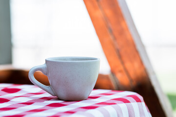 cup on the background of a checkered tablecloth on the street, coffee on a picnic