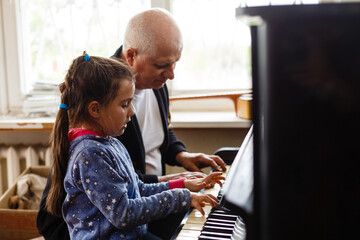 grandfather teach girl playing the piano happily