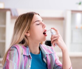 Young woman using inhalator to cope with asthma