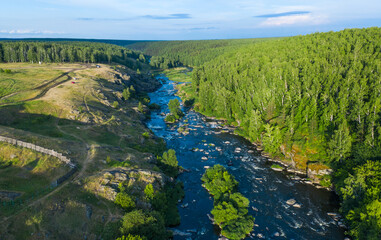 Fototapeta na wymiar soft sun rays in evening over beautiful valley with a mountain river and many rapids. Ural, Russia, view from drone.