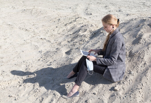 freelance and remote work.business woman in stylish business suit with laptop sitting in desert sand. Female student online training education abroad