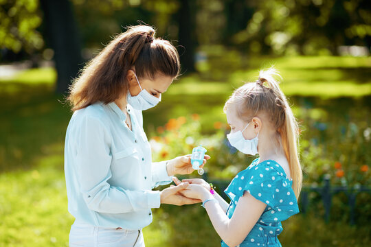 elegant mother and daughter disinfecting hands with sanitizer