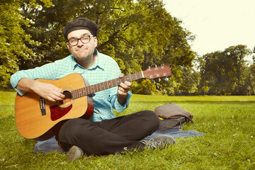 Funny man on city park summer meadow enjoying day with guitar