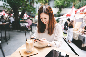 Young adult asian woman using smart phone at outdoor cafe on weekend