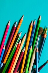School supplies- pens, pencils, brushes on a green background. The view from the top.