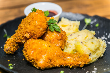 Fried chicken with potato on black plate.The food in the restaurant. Food styling and restaurant meal serving. 