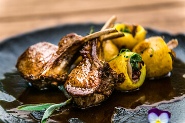 Roasted lamb ribs with stuffed potato on black plate. The food in the restaurant. Food styling and restaurant meal serving. 