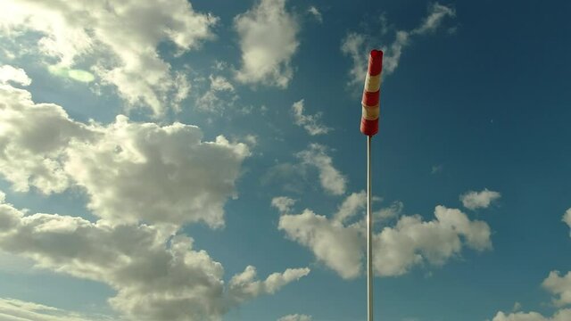 Aerodrome windsock, used to indicate wind speed and direction. Windsock on the background of sky with clouds 