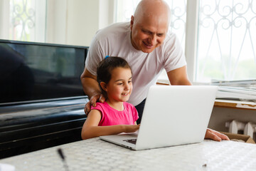 Granddaughter helping grandpa to make online communication on laptop
