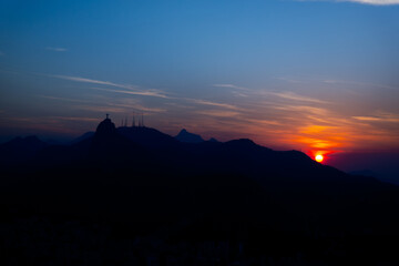 Sunset, right side, corcovado and mountains in silhouette with blue and red sky seen from Niteroi, Rio de Janeiro, Brazil