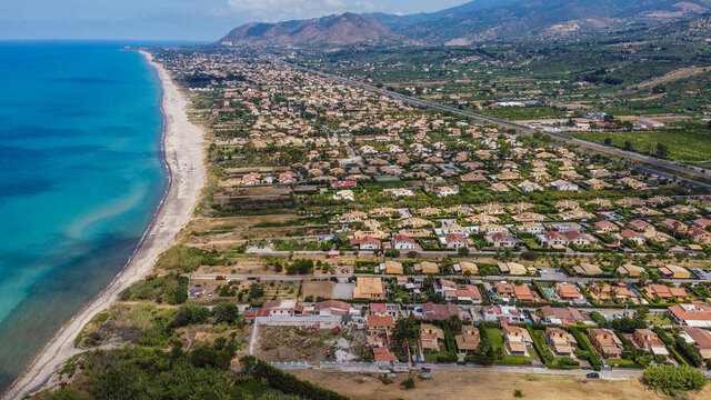 Aerial view of the Villa in Campofelice di Roccella in Sicily, under a beautiful sunny sky, with swimming pools and trees.