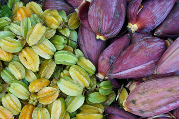 Fototapeta na wymiar Starfruit (carambola) and banana flowers for sale in market, Laos