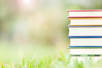 Colorful books stacked on the grass with green background