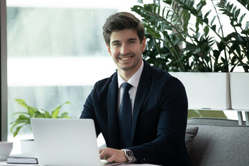 Happy businessman in formal wear using laptop. Portrait of young handsome business man wearing...