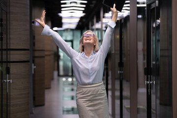 Happy excited senior business woman triumphing in office. Older businesswoman cheering after...