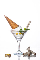 A glass of ice cream with a waffle cone and cherry horn, on a white background.