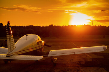 Fototapeta na wymiar Quadruple aircraft parked at a private airfield. Rear view of a plane with a propeller on a sunset background.