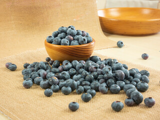 Fresh blueberries in wooden bowl. Rustic setting.