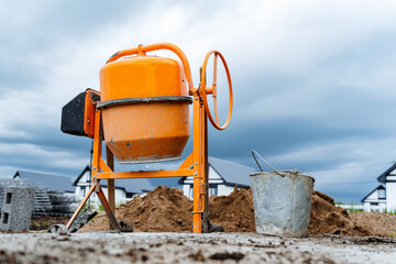 an orange concrete mixer where cement is prepared for construction works stands on the street